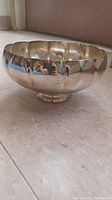 Side view of silver plated pedestal bowl showing scalloped rim and reflective surface.
