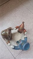 Top-down view of the three snowman figurines holding hands around the tealight holder base on floor.