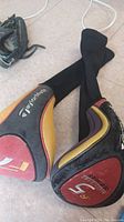 Two Taylor Made golf club covers with black, red, yellow, and gray colors, showing logos and size markings.