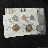 Seven Canadian coins from 2002 in uncirculated condition, sealed in clear plastic packaging including informational insert and sealed backing card.