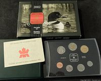 Photo of the 2002 Royal Canadian Mint Specimen Coin Set box with a loon photograph, green padded case and booklet alongside a black tray containing eight coins in a protective display.