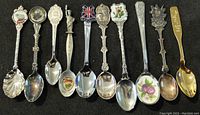 Wide view showing entire lot of 10 assorted collector spoons with various decorative handles and themes