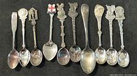 Photo showing full set of 8 souvenir collector spoons with various decorative handles.
