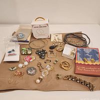 Full view of assorted costume jewelry including earrings, necklaces, brooches, pins, pendants and bracelets on a brown background.