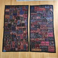 Two patchwork fabric wall hangings laid side by side on floor, showing overall design and colors