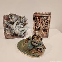 Fairy, tree plaque, and flower pottery art pieces arranged on white surface