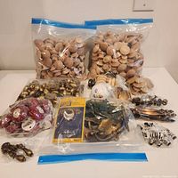 Full lot displayed showing two large bags of small unfinished wood knobs, one half bag of vintage brass knobs, multiple smaller bags of red wood knobs, a large ceramic knob, packaged gold drawer pulls and various vintage door pulls and hardware pieces.