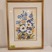 Framed watercolor painting of blue and white flowers with orange accents, showing full artwork and frame.