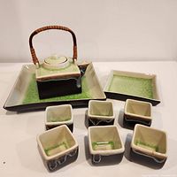 Full tea/saki set arranged with teapot, six cups, and two plates showing green crackle glaze and unique color contrast