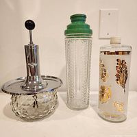 Three vintage bar pieces: pumped decanter, cocktail shaker, decorative bottle