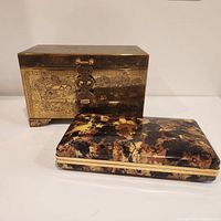 Vintage brass jewelry box with intricate engravings and brass latch along with a separate vintage marbled travel jewelry case