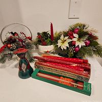 Lot showing all items on white surface including ceramic sleigh with floral arrangement, white candle holder with taper candle, signed figurine, box of red wax tapers and snowman candles