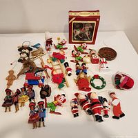 Full view of all vintage ornaments arranged on a flat surface, showing variety of figures including Santas, elves, an angel, clowns, and cultural dolls.
