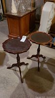 Pair of vintage wooden side tables with scalloped edges and dark leather tops, set on central pedestal tripod bases in a medium brown finish.