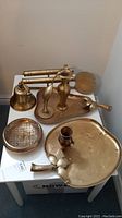 Includes all nine brass items arranged on a small table showing the bell, vases, platters, bird, incense burner, and sconces together.