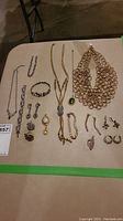 Overview of multiple necklaces, bracelets, and earrings laid out on table.