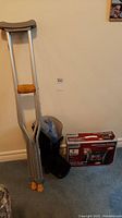 Photo showing one pair of aluminum adjustable crutches, black foot boot, and boxed back massager on carpet.