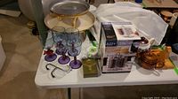 Wide angle photo showing entire lot contents including tea pots, coffee carousel box, glasses, and trays.