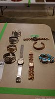 Full overview of four bangle watches, four wrist watches, and one bracelet arranged on a table.