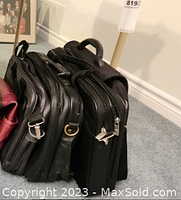 Photo showing four black laptop bags stacked side by side, with varying styles of handles and zippers