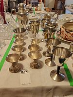 Overview of the silver-plated barware items including cocktail shaker, pitcher, and rows of goblets and cordial cups