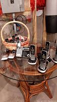 Five Panasonic cordless handsets and bases, four Motorola handsets in a basket on a glass table in basement