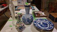 Photo showing two porcelain vases, a larger blue and white James Kent vase and a smaller multicolor Chinese Wucai glazed vase, along with the white Royal Leerdam crystal Madonna and Child sculpture in the background.