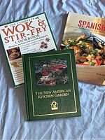 Photo showing front covers of three cookbooks: The Complete Wok & Stir-Fry Cookbook, Spanish Cuisine cookbook, and The New American Kitchen Garden.
