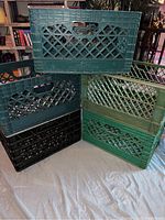 Five plastic crates stacked and arranged showing the lattice pattern and different shades of green and black.