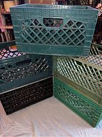 Five plastic crates stacked and arranged on floor, showing different colors and lattice side pattern