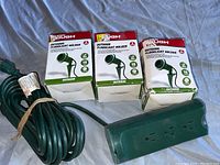 Six boxed outdoor floodlight holders and a green outdoor power cord with three outlets.
