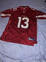 Front view of red Arizona Cardinals jersey with number 13, worn but in good condition.