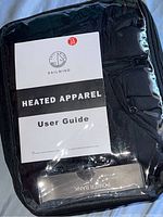 Heated apparel packaged in clear plastic showing Sailwind User Guide and power bank inside.