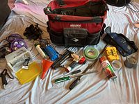 Full view of the Husky roll tool bag and contents displayed on a white sheet including screwdrivers, caulking gun, tapes, spray paint, gloves, and more.