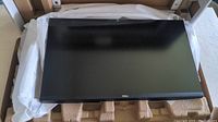 Dell 27-inch monitor panel displayed inside protective packaging showing slim bezel and black finish with Dell logo on front bottom bezel.
