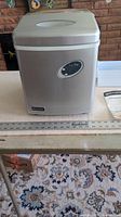 Front and top view of the Emerson portable ice maker with steel exterior and digital control panel.
