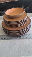 Stack of dishes including one bowl on top of plates with ruler measuring stack