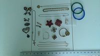 Overview of the mixed jewelry lot on a white surface showing necklaces, pins, earrings, and glass bangles.