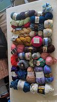 Full assortment of 35 skeins of yarn in varied weights, colors, and fiber types laid out showing diversity of skeins in the lot.
