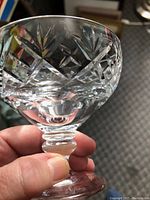 Close-up image showing detailed cut etching on the crystal glass bowl and thick stem base held in hand.