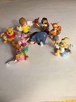 Overview of all 8 Disney Winnie the Pooh character figures arranged in a group on a flat surface.