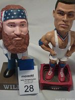 Photo of Willie Nelson and Kurt Angle bobblehead nodders on bases showing details and condition.