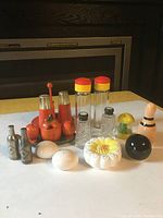 Full assortment of vintage salt and pepper shakers and condiment sets arranged on a table in front of a dark fireplace, showing variety of shapes, colors, and materials.
