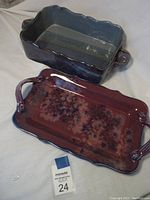Two pottery serving dishes; one rectangular with handles and floral pattern, one square with scalloped edges and textured interior.
