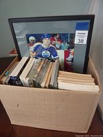 Box containing the signed framed hockey photo and media guides stacked beside it