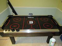 Wilson air hockey game table showing top playing surface with paddles and pucks in place