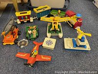 Overview of lot showing Fisher Price train set, camping truck, sea plane with broken propeller, figures, and toy boat with crane.