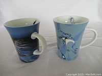 Front view of two indigenous art ceramic mugs by Rick Beaver, showing unique blue-themed artwork on each.