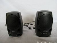 Front view of both Sony black computer speakers with cables, volume knob, and headphone jack visible on one.