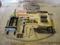 Complete view of all items in the lot spread on a cloth with visible packaging for Quick Action vise and metal bender and all accessories and tools.